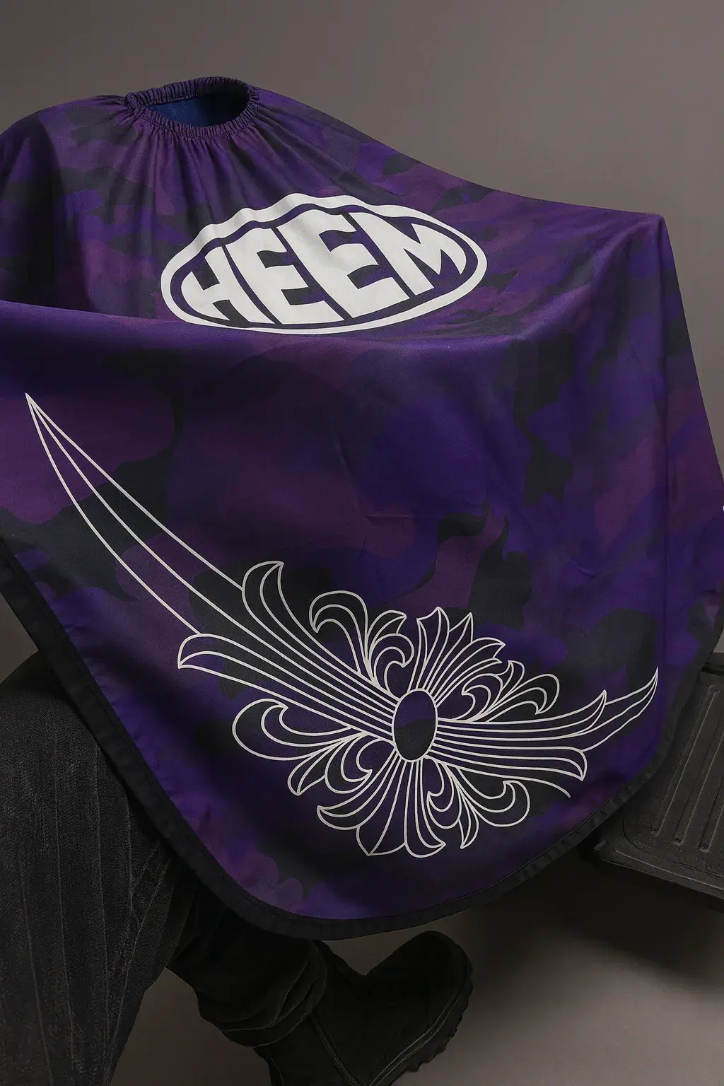 The purple HEEM Cape draped over a barber chair