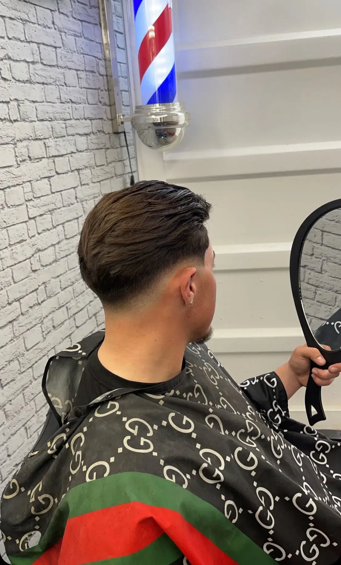A barber styling a client's hair with a HEEM comb in the shop